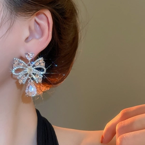 Detailed view of silver bow drop earrings with sparkling rhinestones and waterdrop pendant