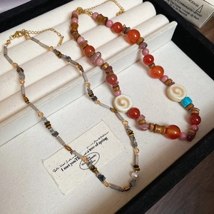 Detail of beaded necklaces with natural agate, colored stones, and white shell pendant