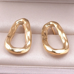 Detail of gold geometric earrings with a hammered lava texture on premium satin lining