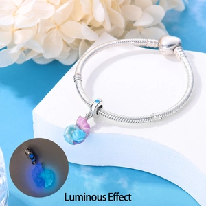 Detailed view of silver snake chain bracelet and conch pendant with luminous glow effect