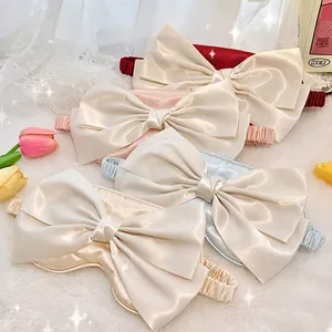 Silk bow sleep mask in multi-color pastel tones on a soft white plush background
