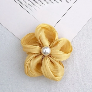 Macro shot of yellow fabric flower accessory with a white pearl center for DIY crafts