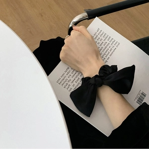 Elegant black satin bow scrunchie accessory worn on wrist for a minimalist sweet style
