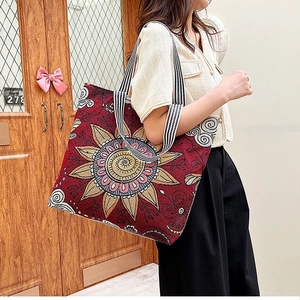 Detail of burgundy floral canvas tote bag showing retro embroidery and striped handles