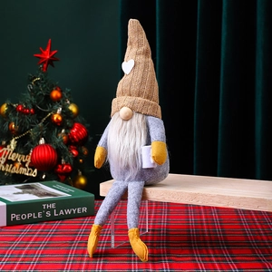 Gnomo navideño de punto hecho a mano sentado en un banco de madera con decoración