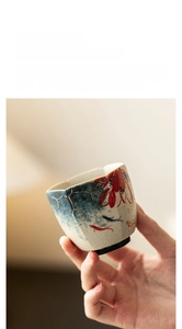 Detailed view of handmade ceramic tea cup with koi fish motifs and hand-painted gold rim