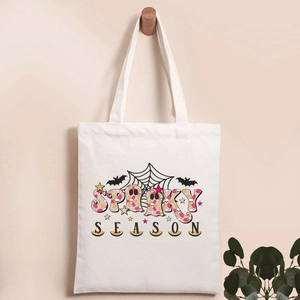 Close-up of Spooky Season pumpkin print on a white canvas tote bag with wooden hook