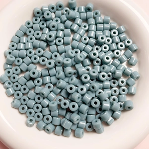 Dettaglio di perline cilindriche in acrilico grigio-blu per gioielli in un vassoio