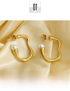 Detail of irregular 18K gold plated hoop earrings with white pearls on satin background