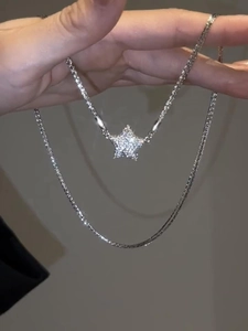 Close-up of a silver star-shaped pendant set with sparkling stones on a stainless steel chain