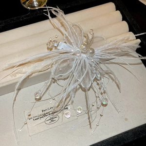 Détail d'une pince à cheveux en plumes blanches avec perles sur support à bijoux