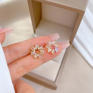 Macro view of gold flower wreath earrings with sparkling rectangle zircon stones