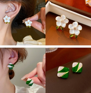 Detail view of vintage enamel flower earrings and geometric green square studs on model