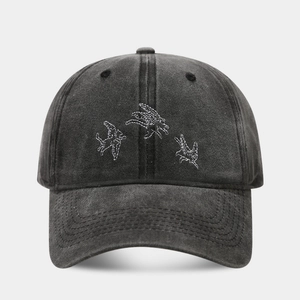 Détail de la broderie de trois oiseaux blancs sur une casquette vintage en coton gris lavé