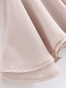 Detail shot of light pink chiffon dress hem showing fine stitching and light texture
