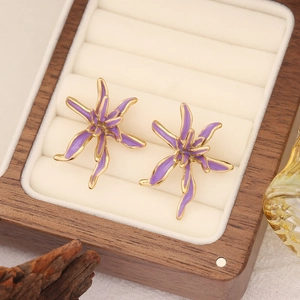 Detail of purple enamel flower earrings with golden metal base on jewelry box display