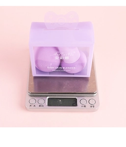 Two purple mushroom head sponges in a clear box shown on a silver digital scale