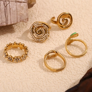 Set of five 18K gold plated stainless steel rings with swirl, knot and daisy motifs