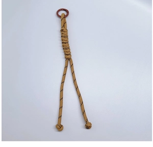 Close-up of khaki paracord bag charm with woven pattern and metallic ring clasp