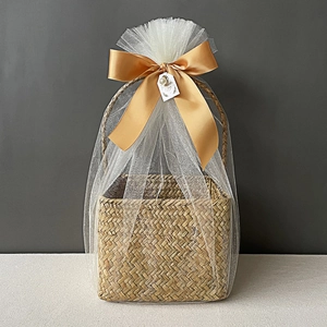 Detail of woven gift basket with white mesh wrap and gold ribbon bow for weddings