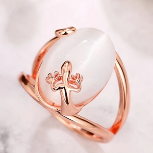 Elegant rose gold lizard ring with large oval white cat's eye stone on marble surface