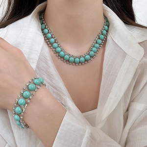 Gros plan d'un mannequin portant un ensemble collier et bracelet turquoise et strass