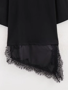 Detail of asymmetrical lace stitching on the hem of a stylish black short-sleeve dress