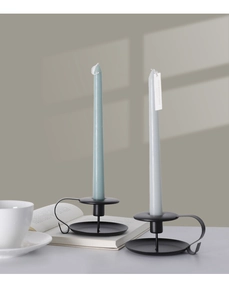 Detail of minimalist black metal candle holders with round handles and taper candles