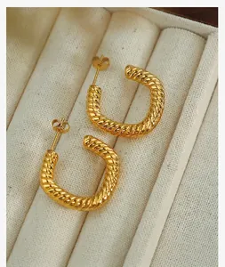 Detailed view of golden twisted hoop earrings on a soft cream jewelry box