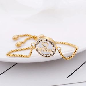 Detailed close-up of gold adjustable bracelet with mother charm and cubic zirconia stones