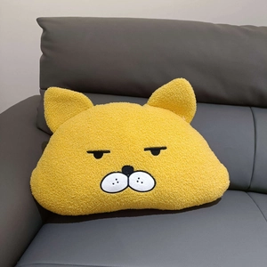Detail of yellow plush cat pillow with a grumpy face embroidery on a grey sofa