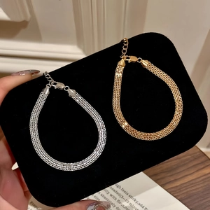Dettaglio dei bracciali a maglia piatta color oro e argento con chiusura a moschettone