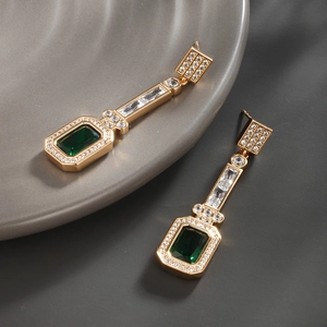 Detailed close-up of emerald green waterdrop earrings with crystals on a ceramic tray