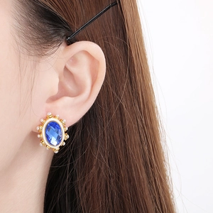 Vintage oval blue glass earrings with gold frame and small pearls on white background