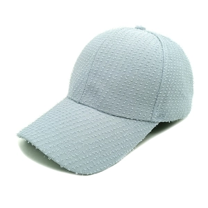 Detail of light blue denim baseball cap showing heavy distressed fringe and textured fabric