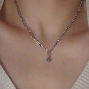 Close-up of asymmetrical mixed chain necklace with small silver ball pendant on model