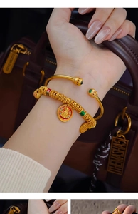 Close-up of 24k gold plated bangle with green stones and red enamel charm bracelet