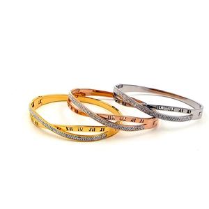 Dettaglio di tre bracciali intrecciati con numeri romani e intarsio di zirconi lucidi