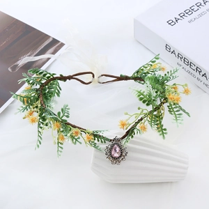 Detail of floral crown featuring pink teardrop crystal and rustic green foliage
