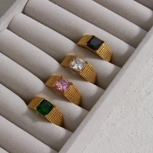 Detailed view of four gold rings with square black, white, pink and green gemstones