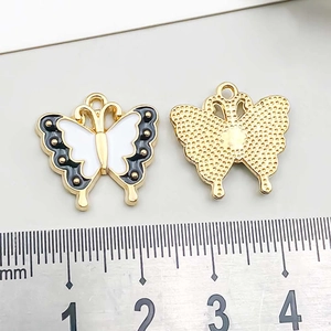 Macro detail of alloy butterfly charm with scale ruler showing 22mm width and 20mm height
