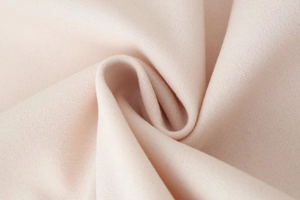 Macro detail of soft light pink wool fabric showing high-quality fiber texture and thickness