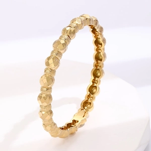 Polished gold geometric faceted ring for women presented on a minimalist white stand