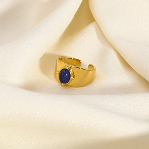 Close-up of gold plated ring with oval blue lapis lazuli on elegant white silk background