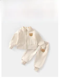 Dettaglio tuta sportiva per bambini crema con ricamo a orsetto e giacca con zip