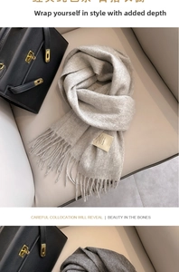 Detail of premium grey wool scarf with fringe tassels next to a luxury leather bag