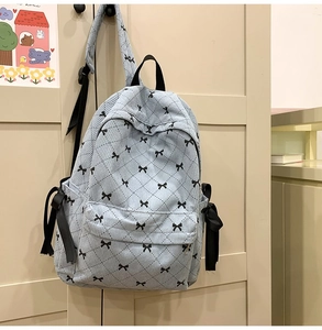 Detail of light blue corduroy backpack with black bow print and diamond quilted pattern