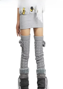Macro shot of grey cable knit leg warmers with faux fur trim and pom-pom details