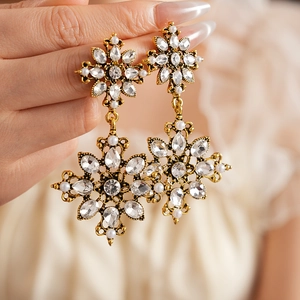 Détail de boucles d'oreilles vintage dorées avec design étoilé, strass et perles