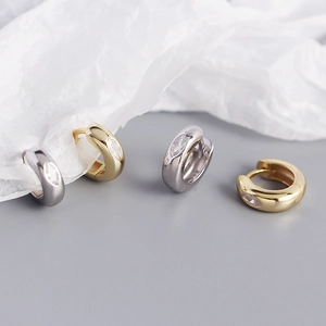 Close-up of gold and silver chunky hoop earrings with marquise-cut zircon stones